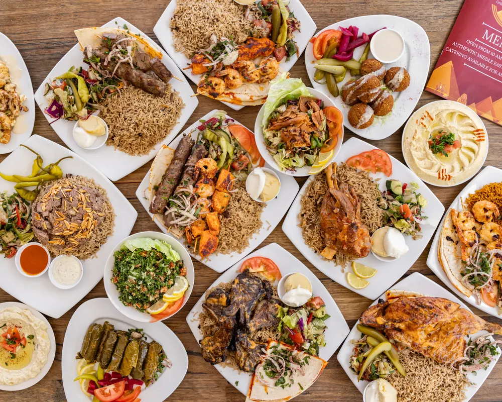 A spread of charcoal chicken, platters, dips and salads on the table at Nile Grill